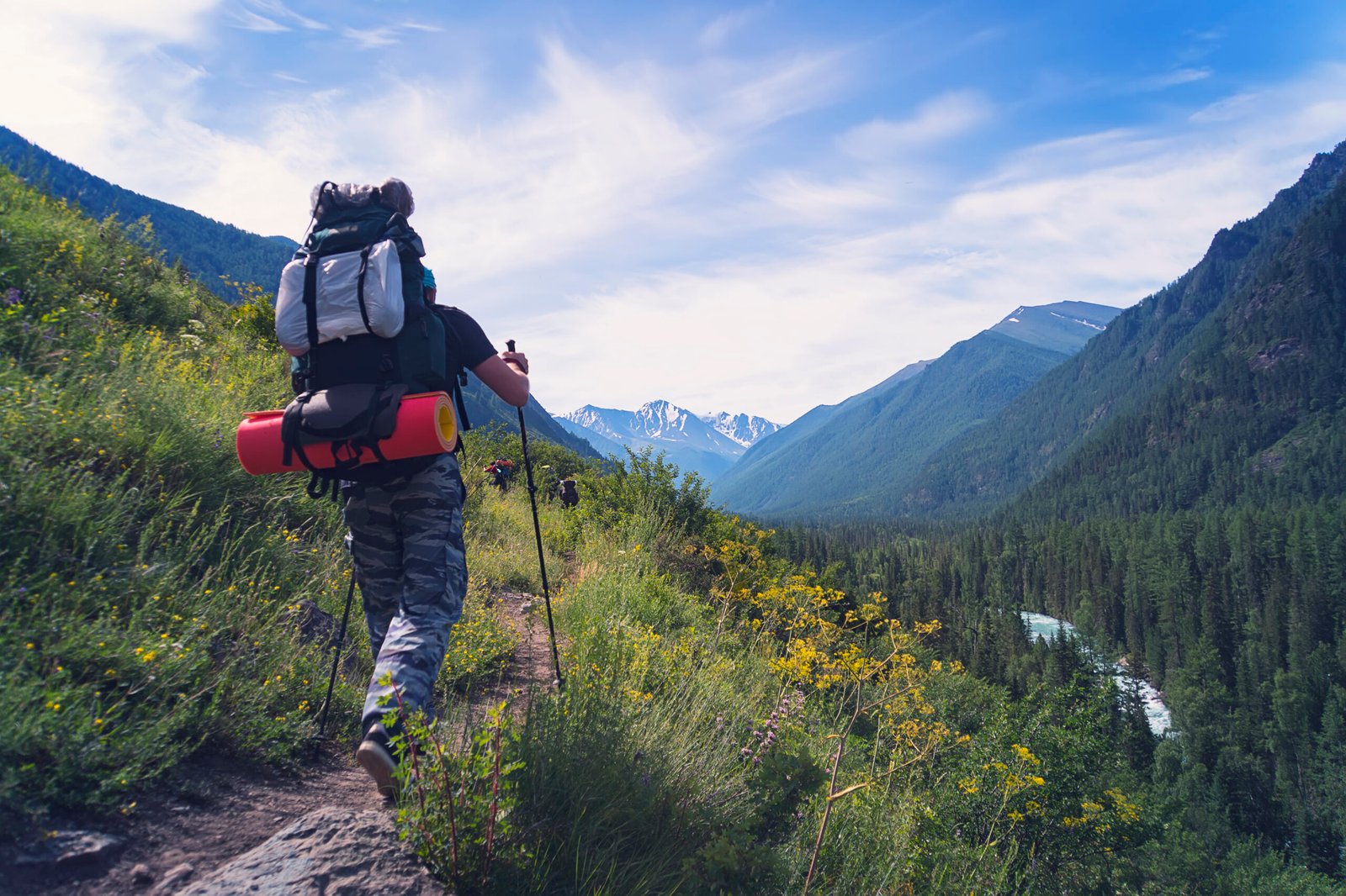 Man hiking at sunset mountains with heavy backpack Travel Lifestyle wanderlust adventure concept summer vacations outdoor alone into the wild. Nordic walking sticks